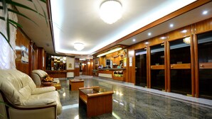 Eine großzügige Lobby mit einer Ledersofa, einem Holzbüro und einem Marmorboden.