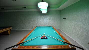 A pool table with balls and cues, a green wall, and a ceiling light fixture.