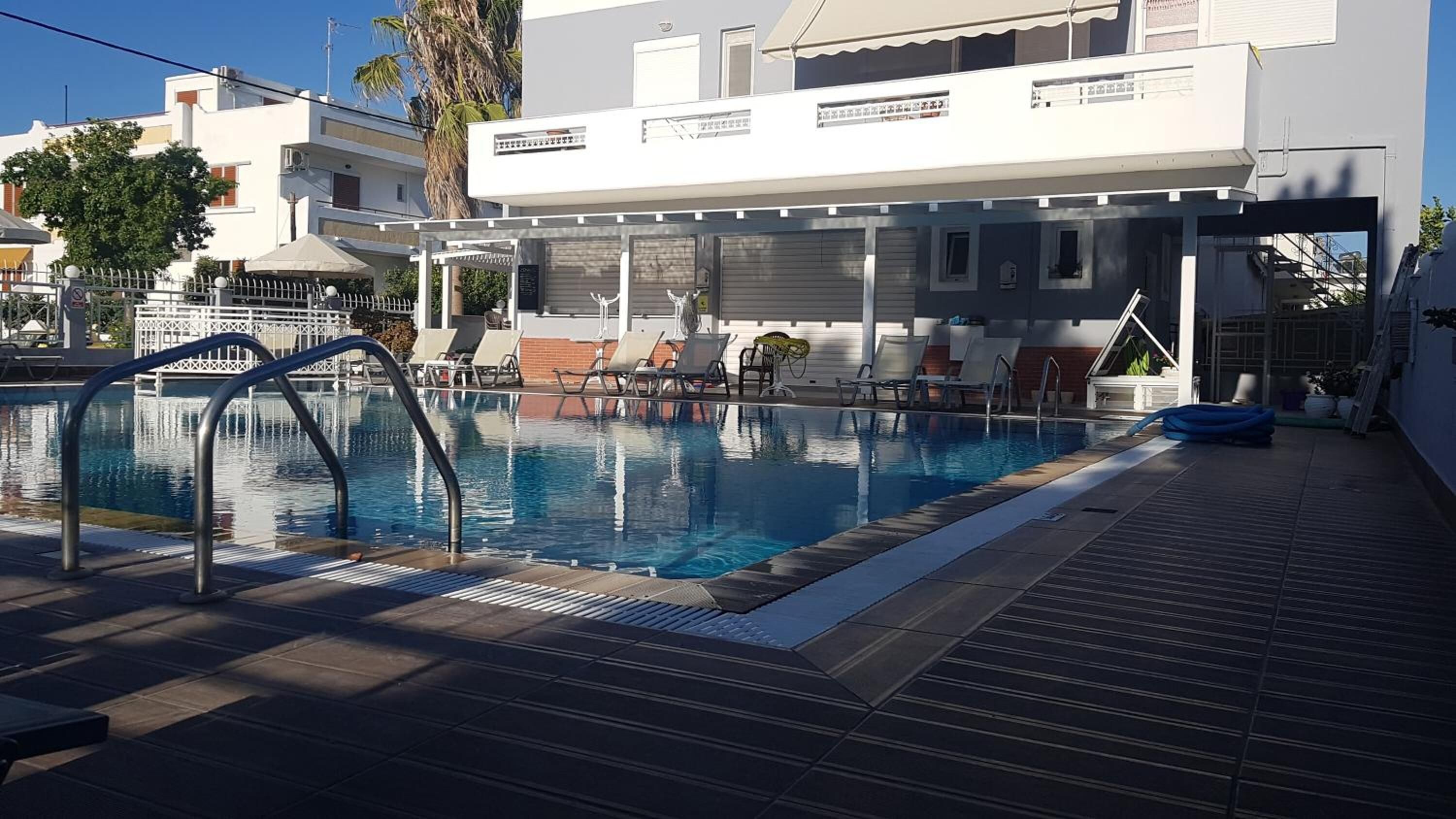 A swimming pool with lounge chairs and a covered area.