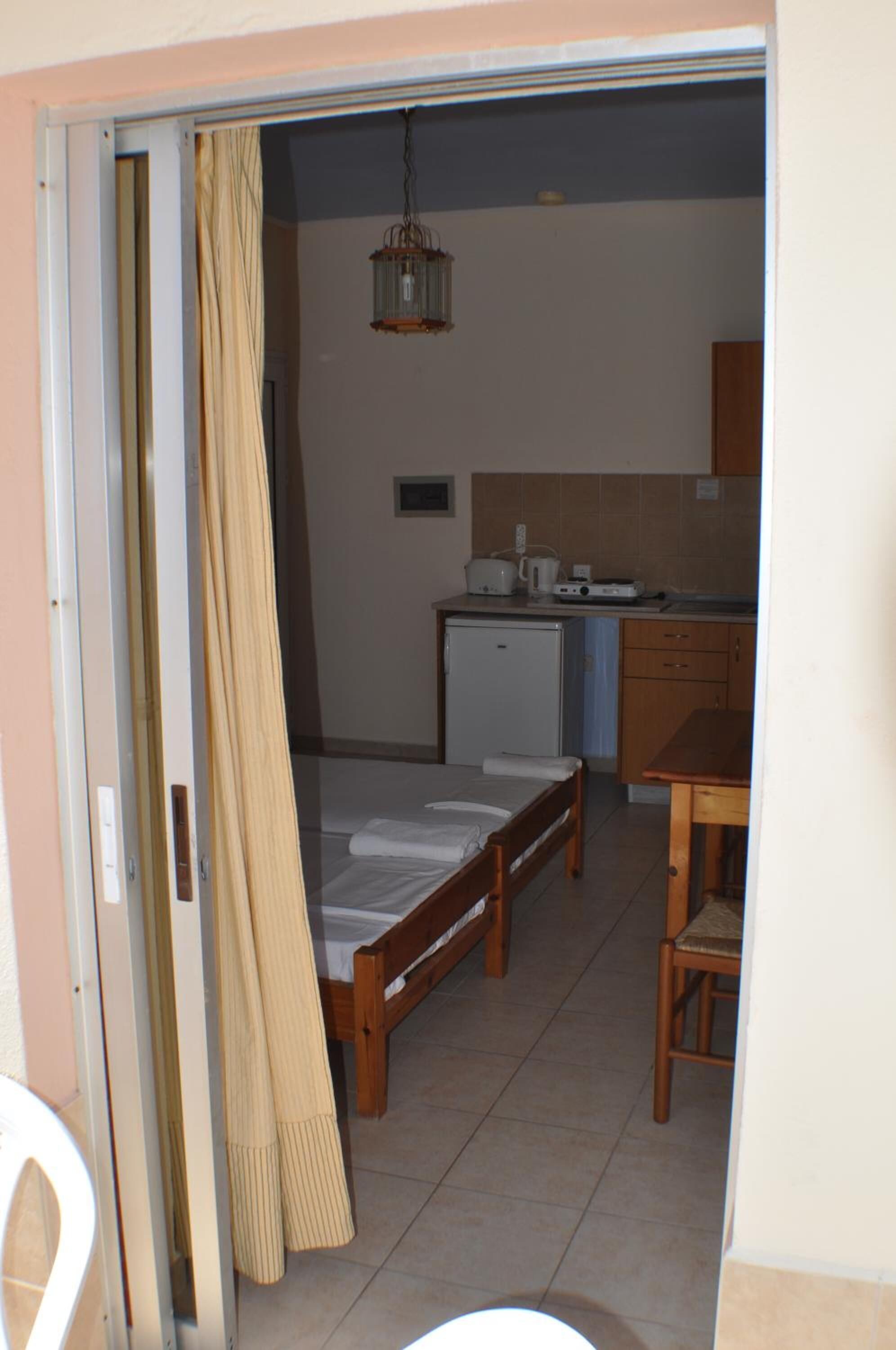A small room with a bed, a kitchenette, and a dining area.