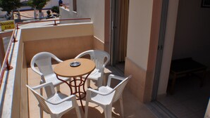 A balcony with a table and four chairs, a door, and a view of a building with domes. - Zouboulia (Kos)