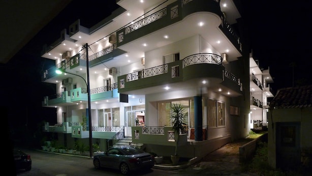 A multi-story building with balconies, a car parked in front, and a well-lit exterior at night. - Pagona Hotel (Istiaia-Aidipsos)