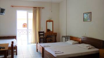 A hotel room with a bed, a desk, a chair, a small table, a mirror, and a painting on the wall.