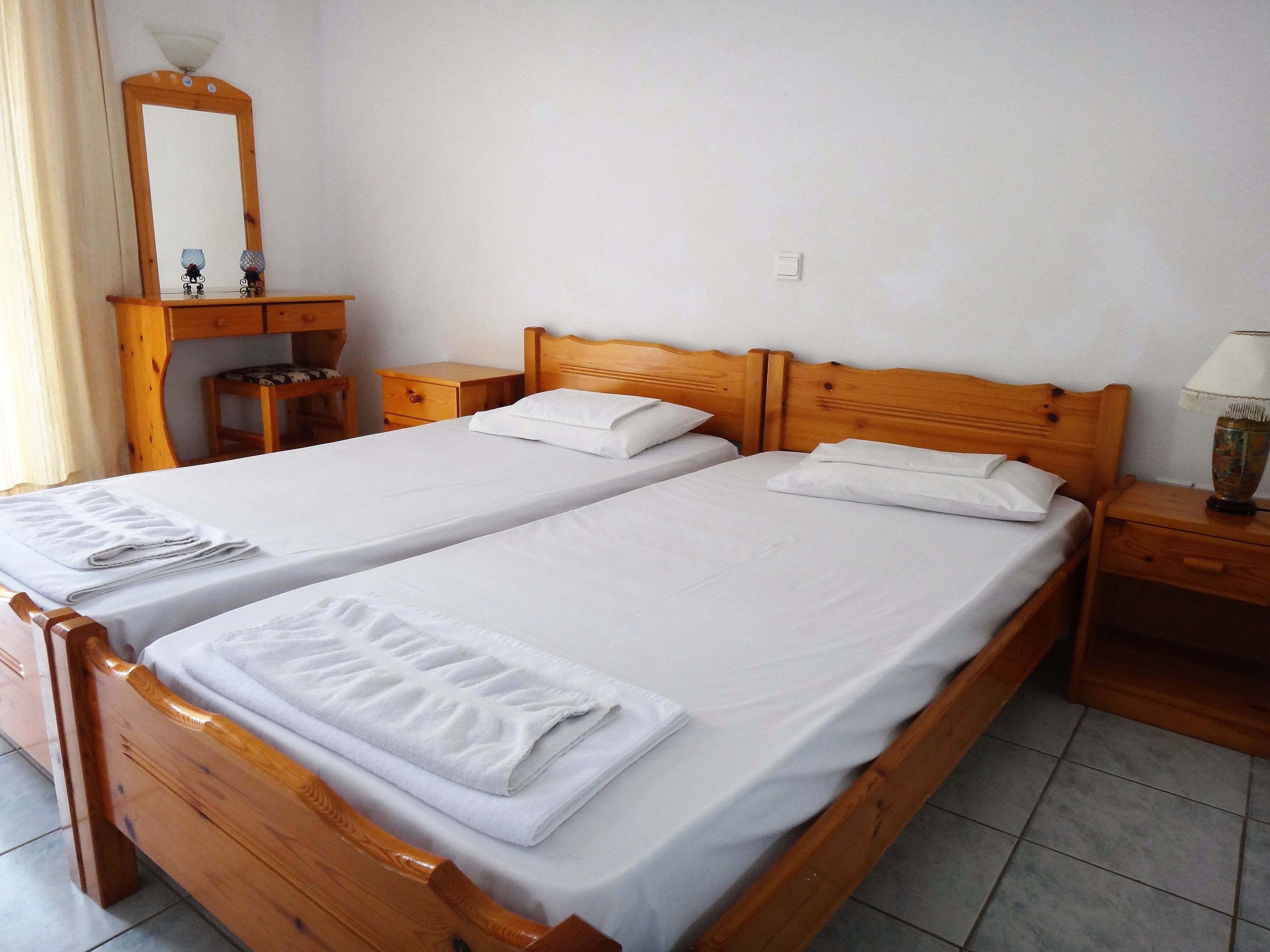 Un lit double avec du linge de lit blanc, une tête de lit en bois et deux tables de chevet.
