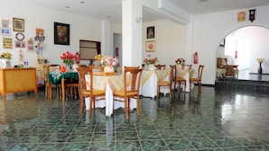 A dining area with marble flooring, wooden chairs, and tables set with flowers. - Pagona Hotel (Istiaia-Aidipsos)