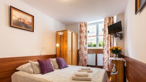 A hotel room with a bed, a wooden wardrobe, a television, and a window with curtains. - Unikat Guest Rooms (Self-check in) (Kraków)
