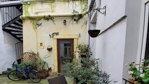 A courtyard with a table and chairs, a bicycle, and potted plants. - Unikat Guest Rooms (Self-check in) (Kraków)