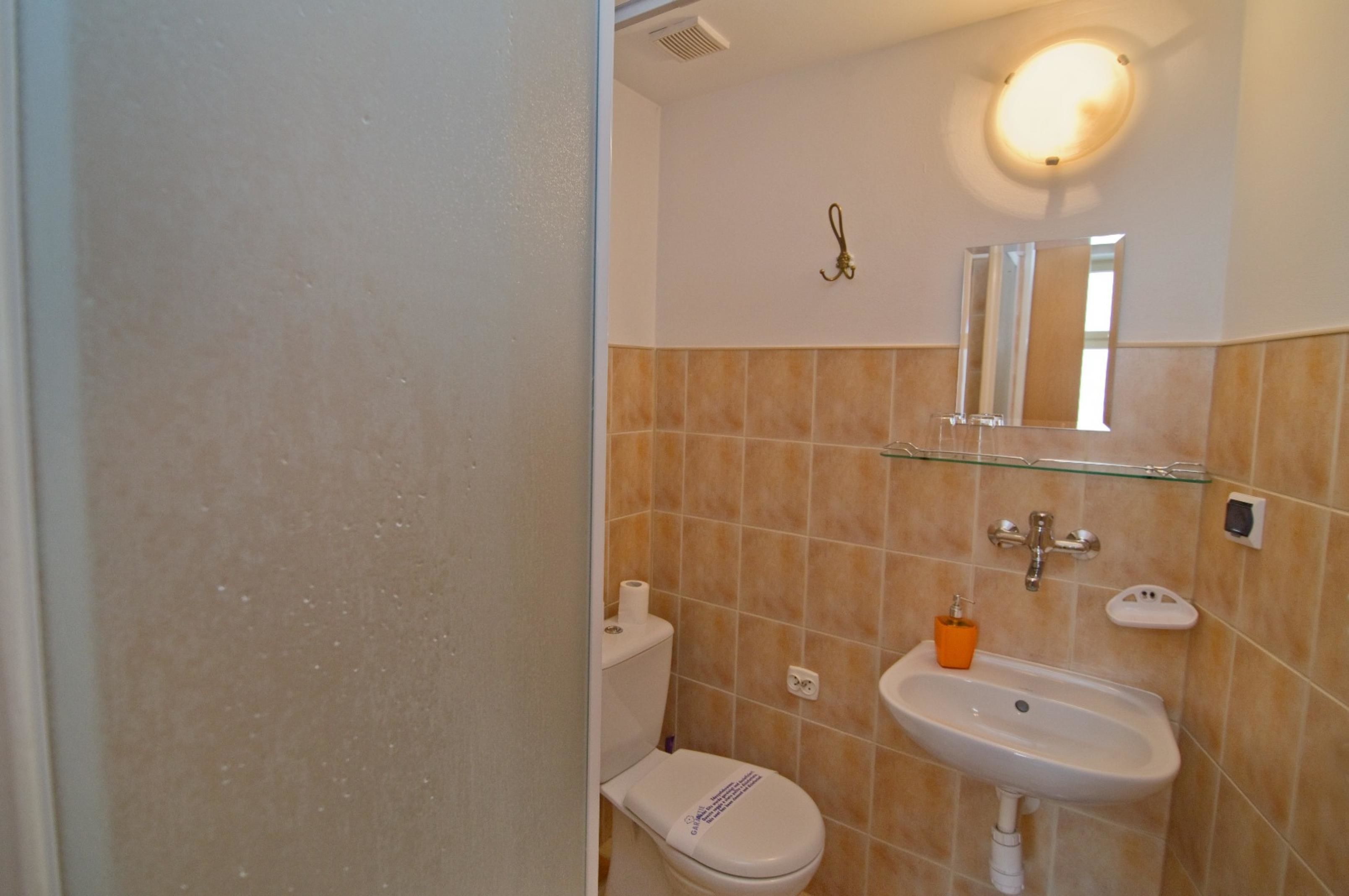 A bathroom with a toilet, sink, and mirror.