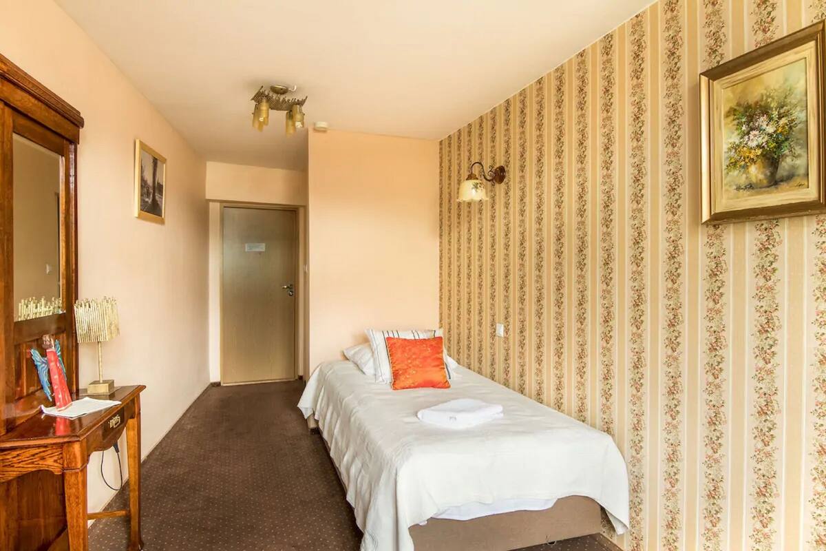 A hotel room with a bed, a desk, a mirror, and a door.