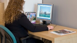 A person sitting at a desk with a computer displaying a travel website, a magazine, and a book titled "EUROPE" on the desk. - Hotel Airmotel (Mestre)