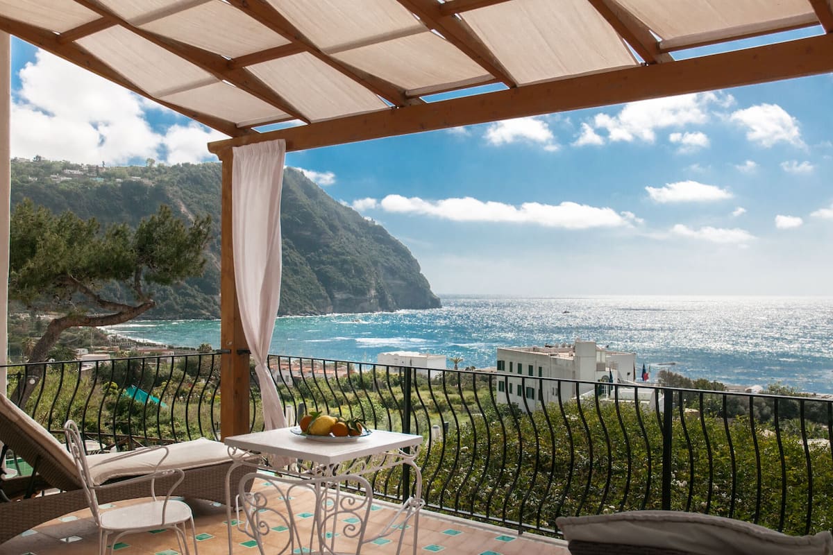 Ein Balkon mit Blick auf das Meer und eine gebirgige Landschaft.