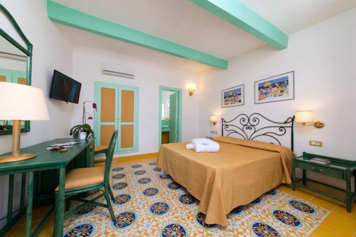 Ein Hotelzimmer mit Bett, Schreibtisch, Stuhl, Fernseher und einem gemusterten Boden.