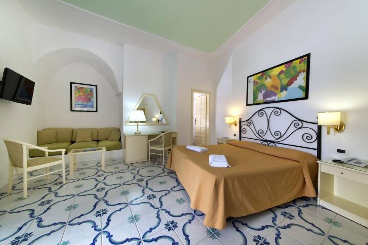 Ein Hotelzimmer mit Bett, Sofa, Schreibtisch und Fernseher.