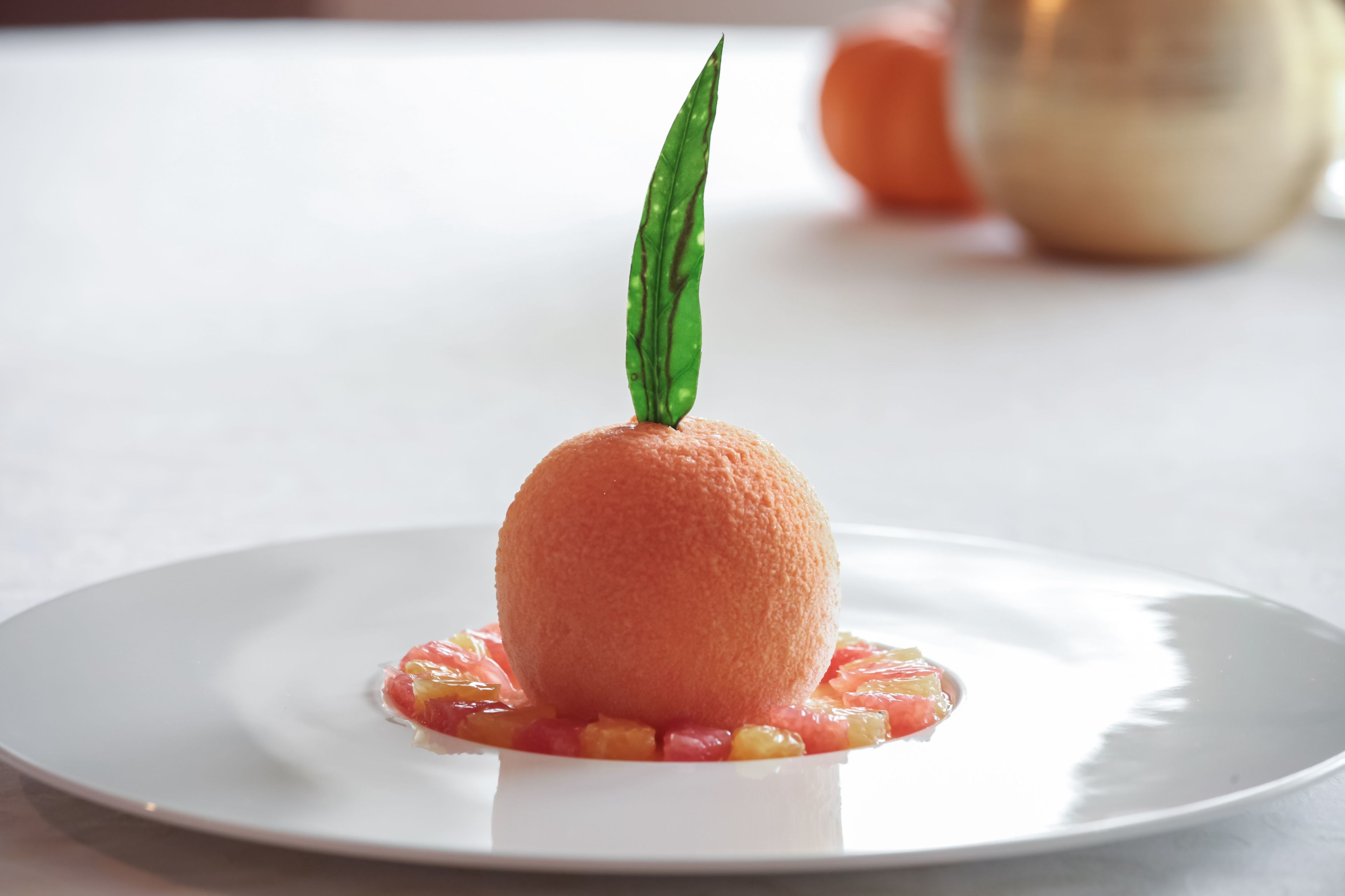 En dessert på en vit tallrik, garnerad med ett grönt blad.