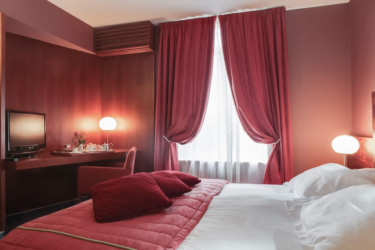 Une chambre d’hôtel avec un lit, un bureau et une télévision.