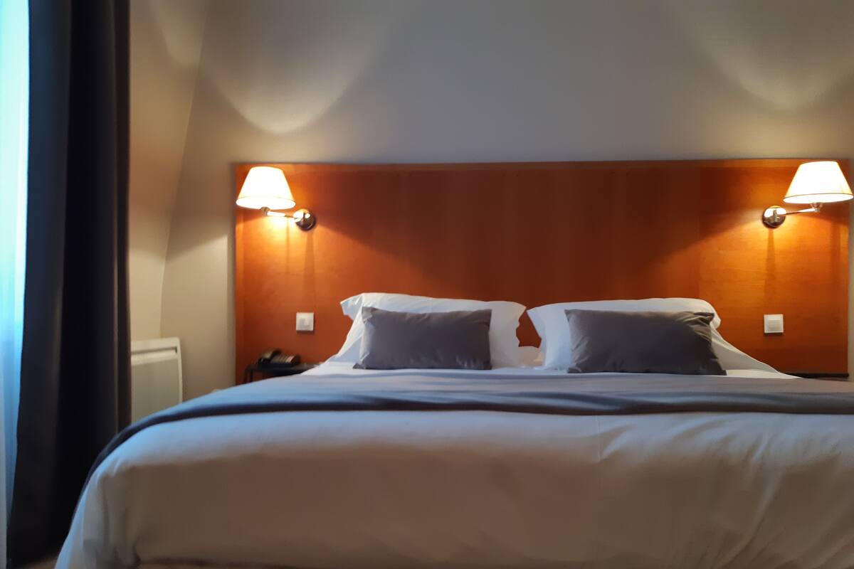 Une chambre d’hôtel avec un grand lit, deux lampes de chevet et une tête de lit en bois.
