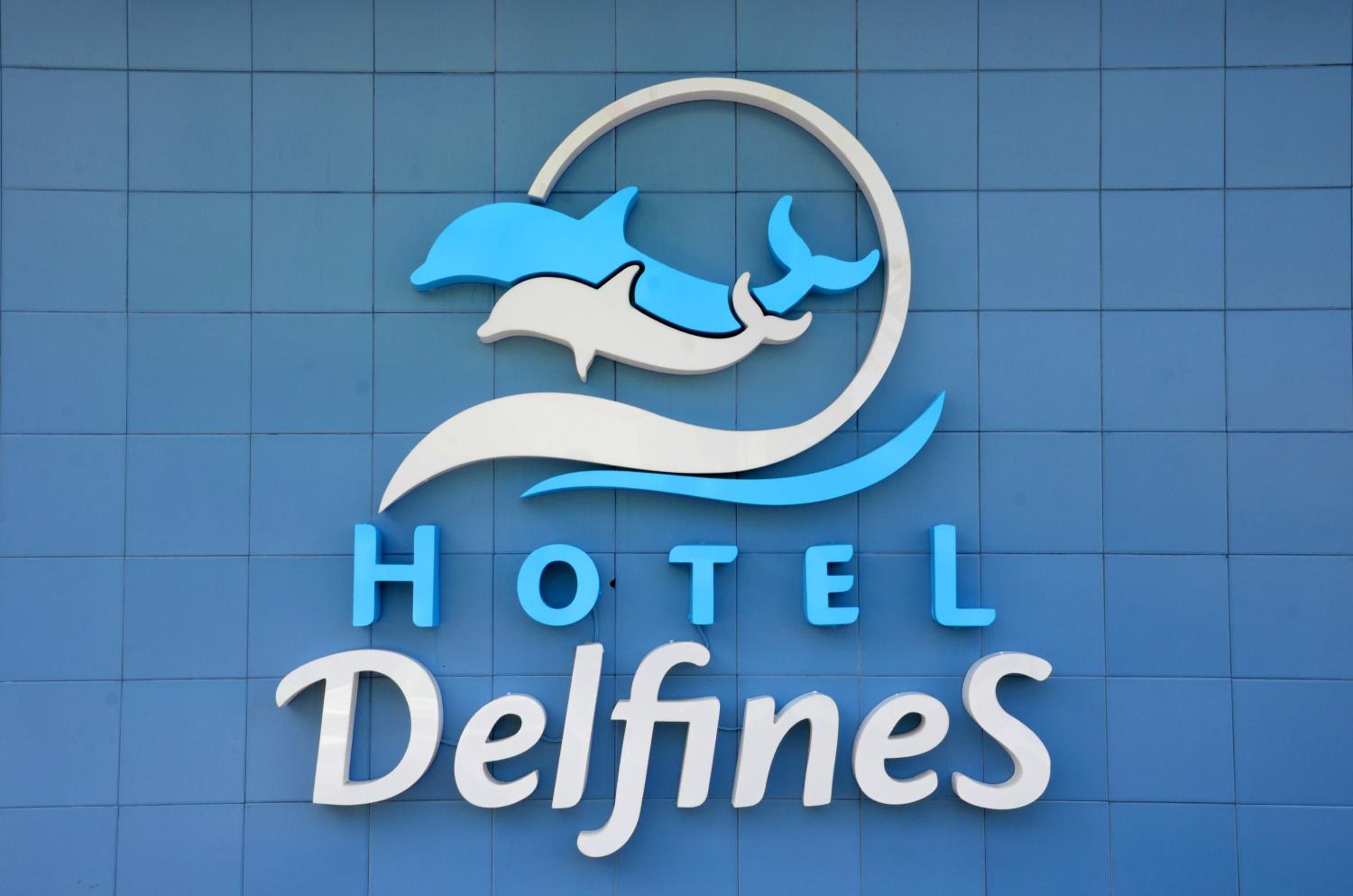 A hotel sign with a dolphin logo and the name 'Hotel Delfines'.