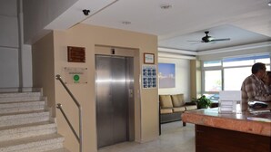A hotel lobby with a reception desk, a staircase, and an elevator. - Hotel Delfines (Veracruz)