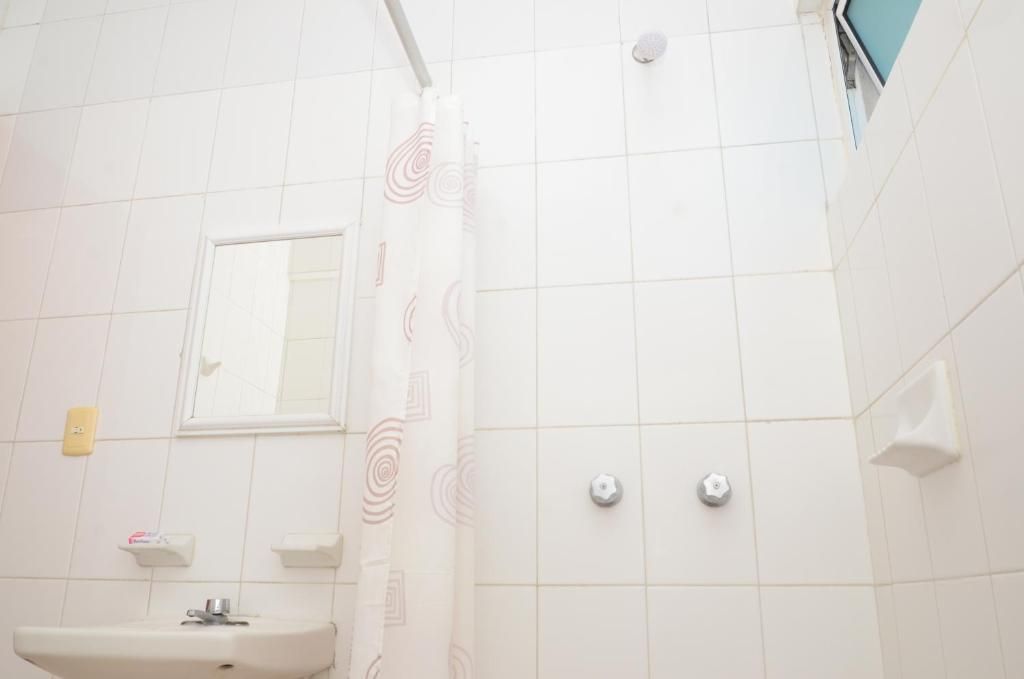 Un baño con lavamanos, espejo, ducha y paredes de azulejos.