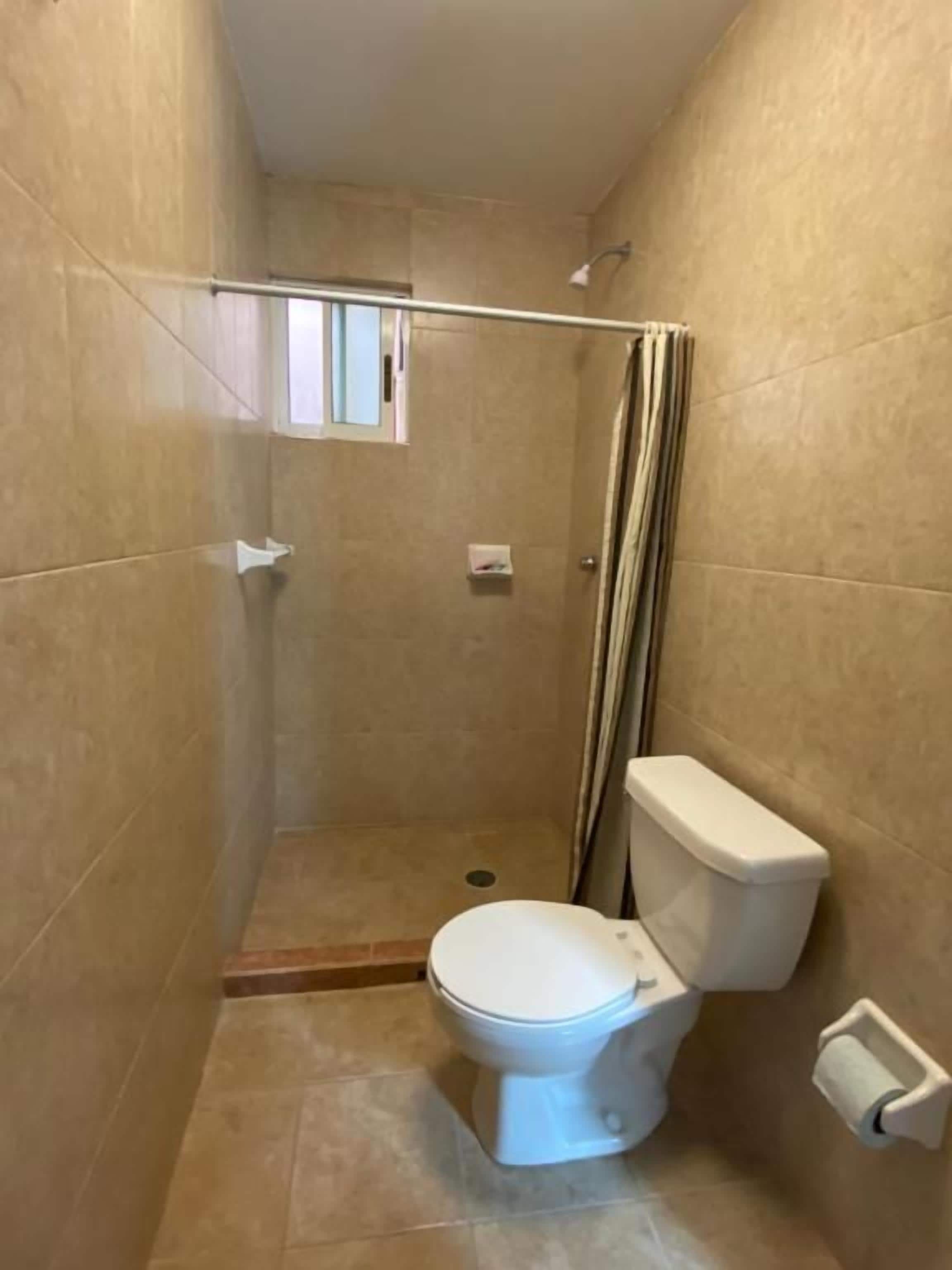 Un baño pequeño y cerrado con inodoro, ducha y cortina.