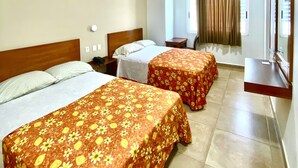 A hotel room with two beds, a ceiling fan, a TV, and a bathroom visible through a door. - Hotel Delfines (Veracruz)