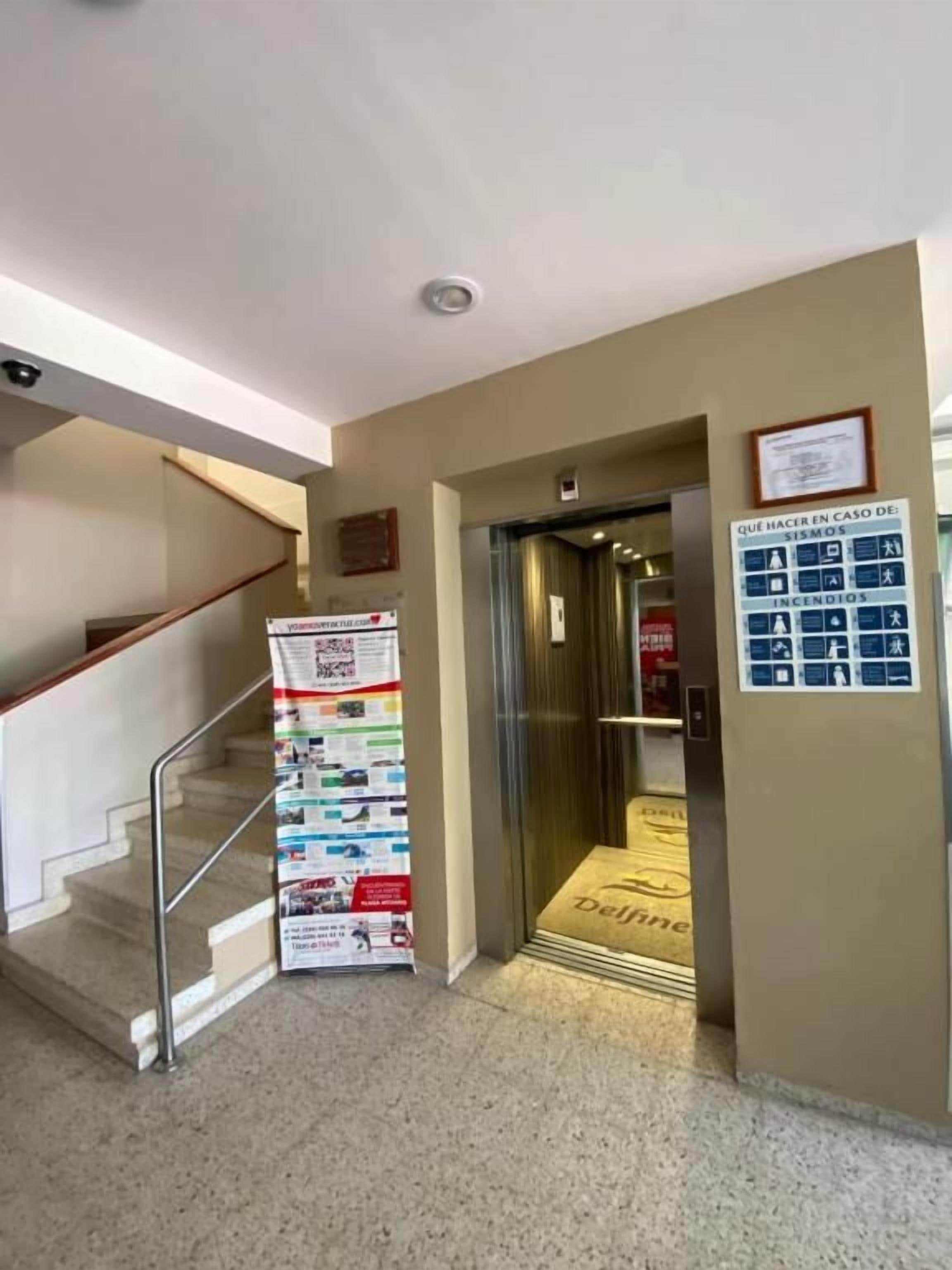 Un vestíbulo de hotel con una escalera, una recepción y un cartel de seguridad contra incendios.