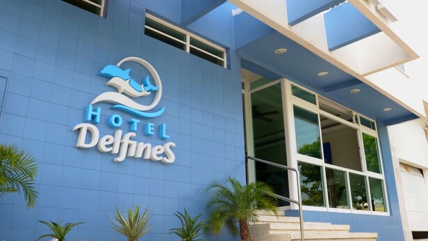 A hotel entrance with a blue facade, a dolphin logo, and the name 'Hotel Delfines'. - Hotel Delfines (Veracruz)