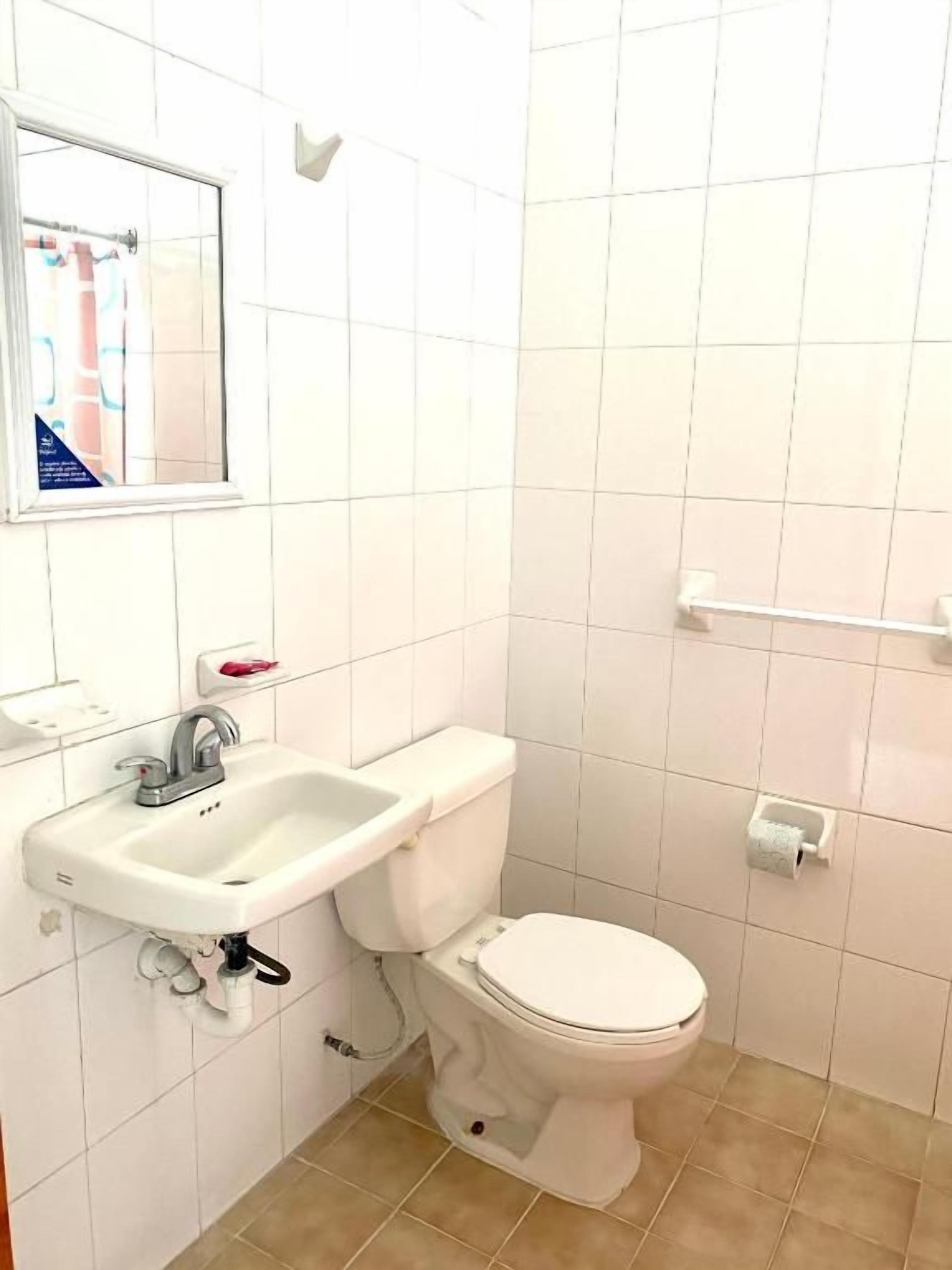 A bathroom with a toilet, sink, and a window.