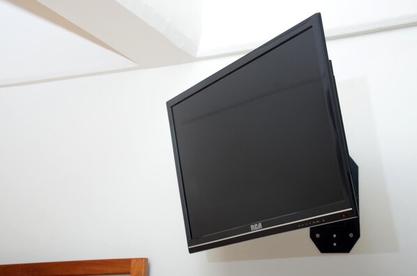 Un televisor de pantalla plana con marco negro montado en la pared, colocado en un ángulo ligero.