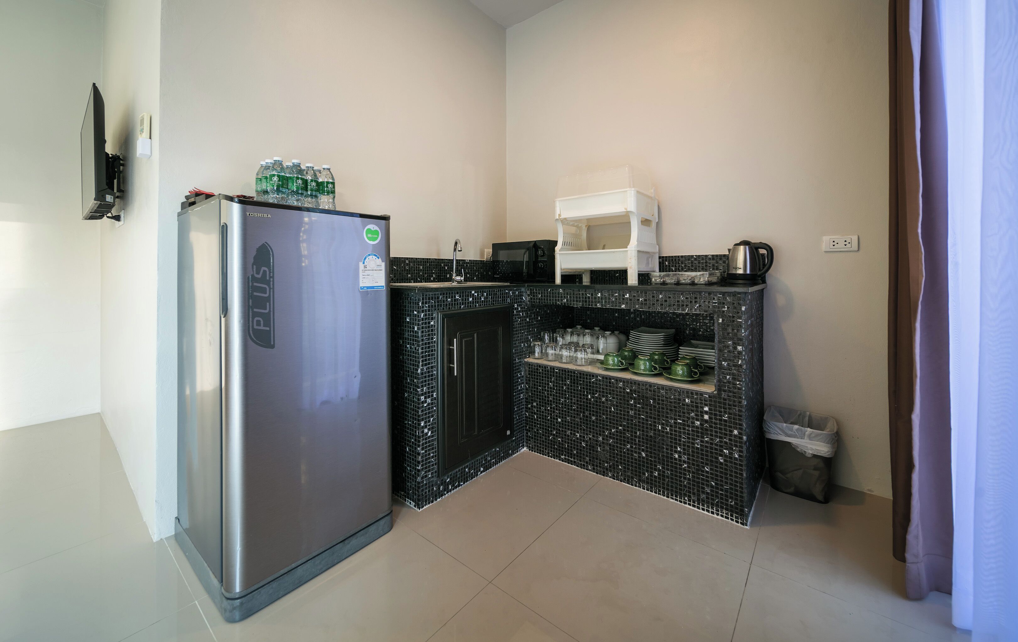 Una cocina compacta con refrigerador, microondas y pileta.