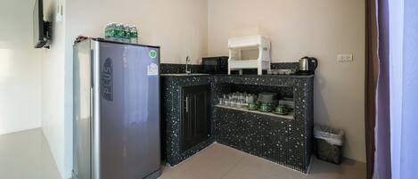 Una cocina compacta con refrigerador, microondas y pileta.