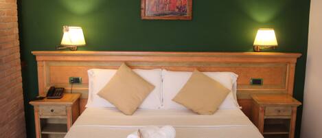 A neatly made bed with two pillows, a bedside lamp, and a folded towel on the nightstand.