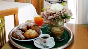 Uma bandeja de café da manhã com doces, café e um vaso de flores sobre uma mesa em um quarto com móveis de madeira e uma porta ao fundo.