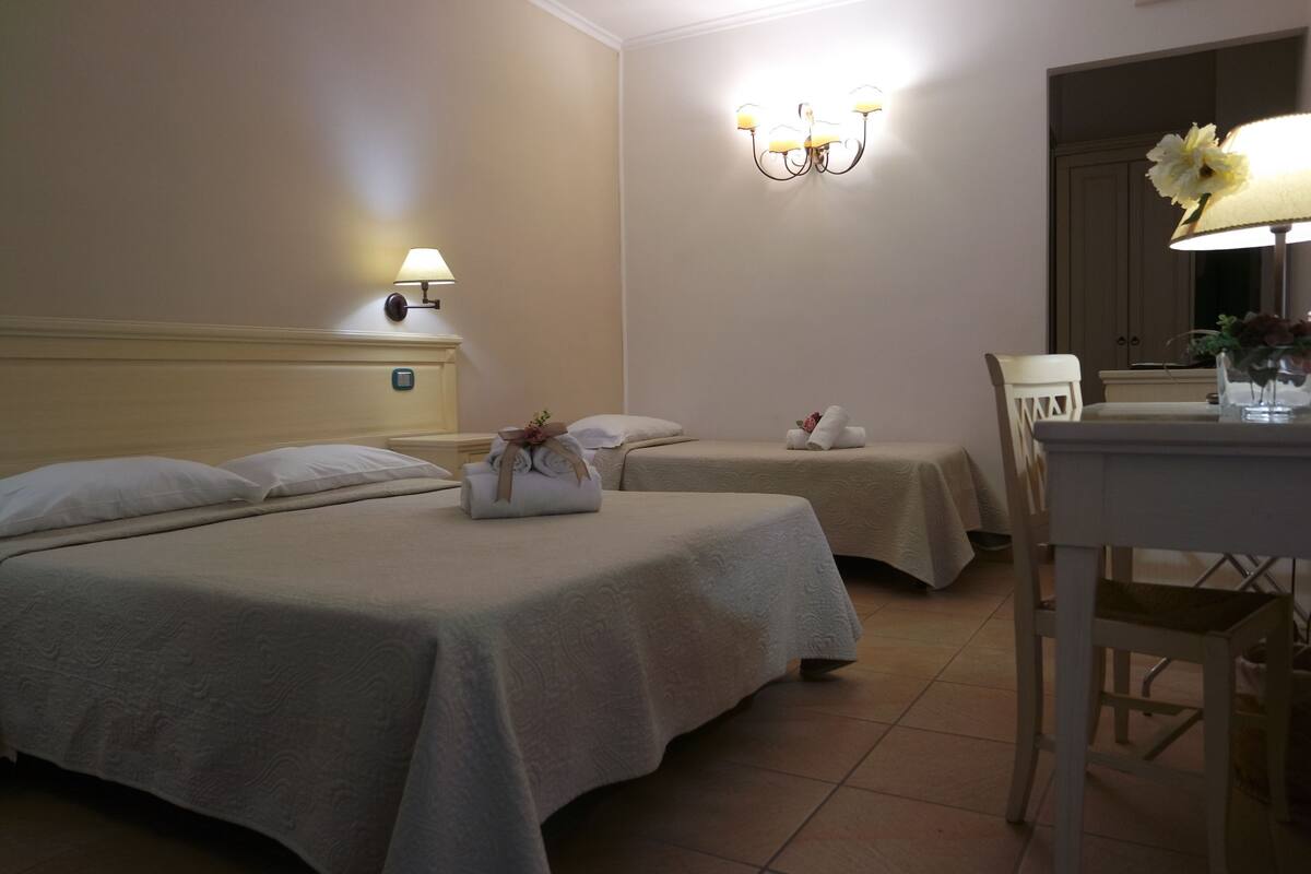 Ein Hotelzimmer mit zwei Betten, einem Schreibtisch, einem Stuhl und einer Lampe.