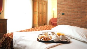 Een hotelkamer met een bed, een ontbijttafel en een bakstenen muur.