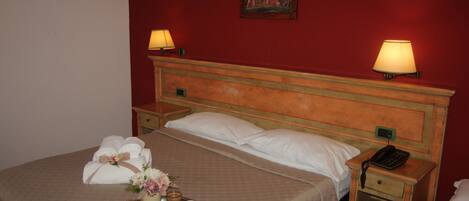 A hotel room with a bed, two bedside lamps, a nightstand with a phone, and a tray with breakfast items.