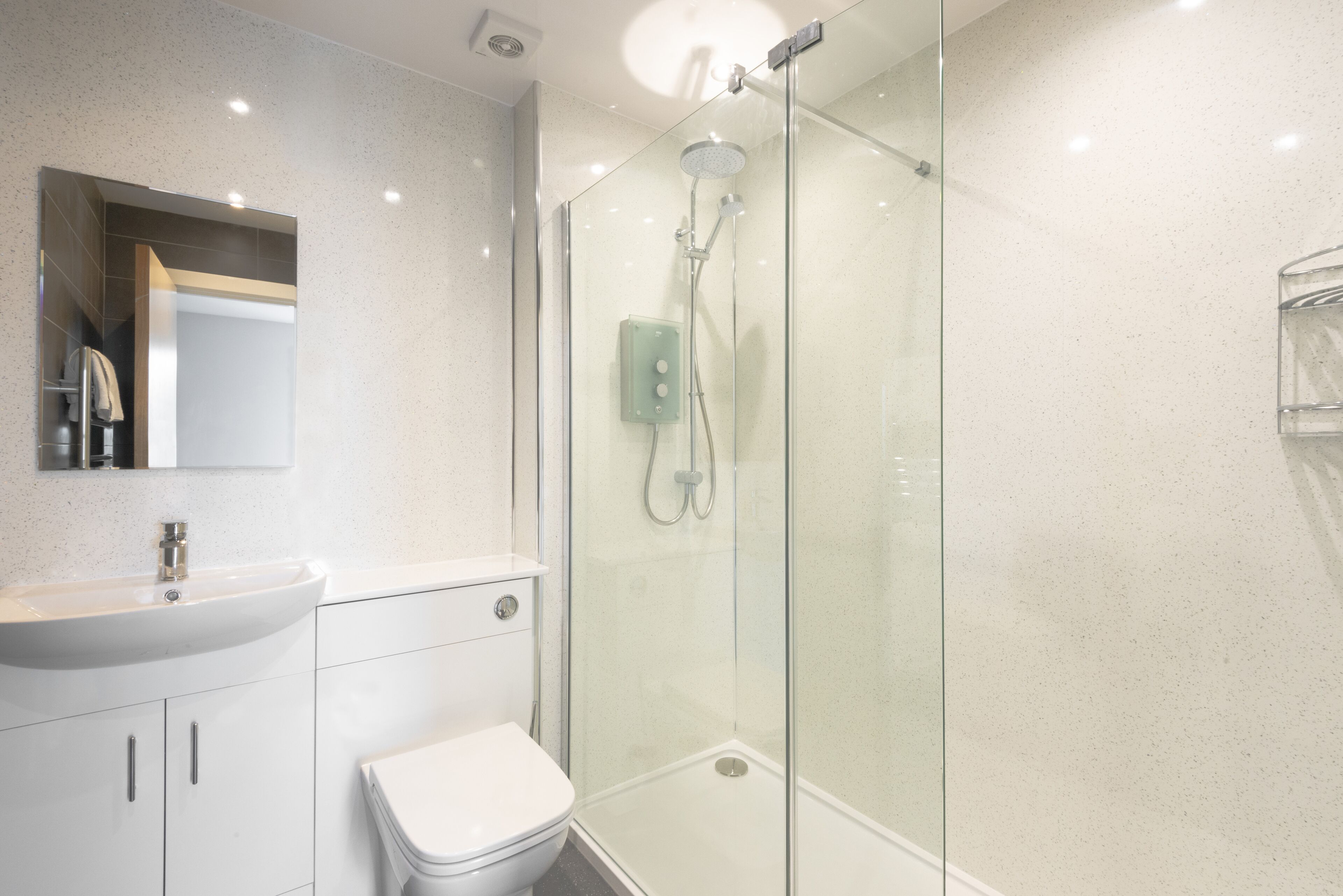 A modern bathroom with a glass-enclosed shower, a white sink, and a toilet.