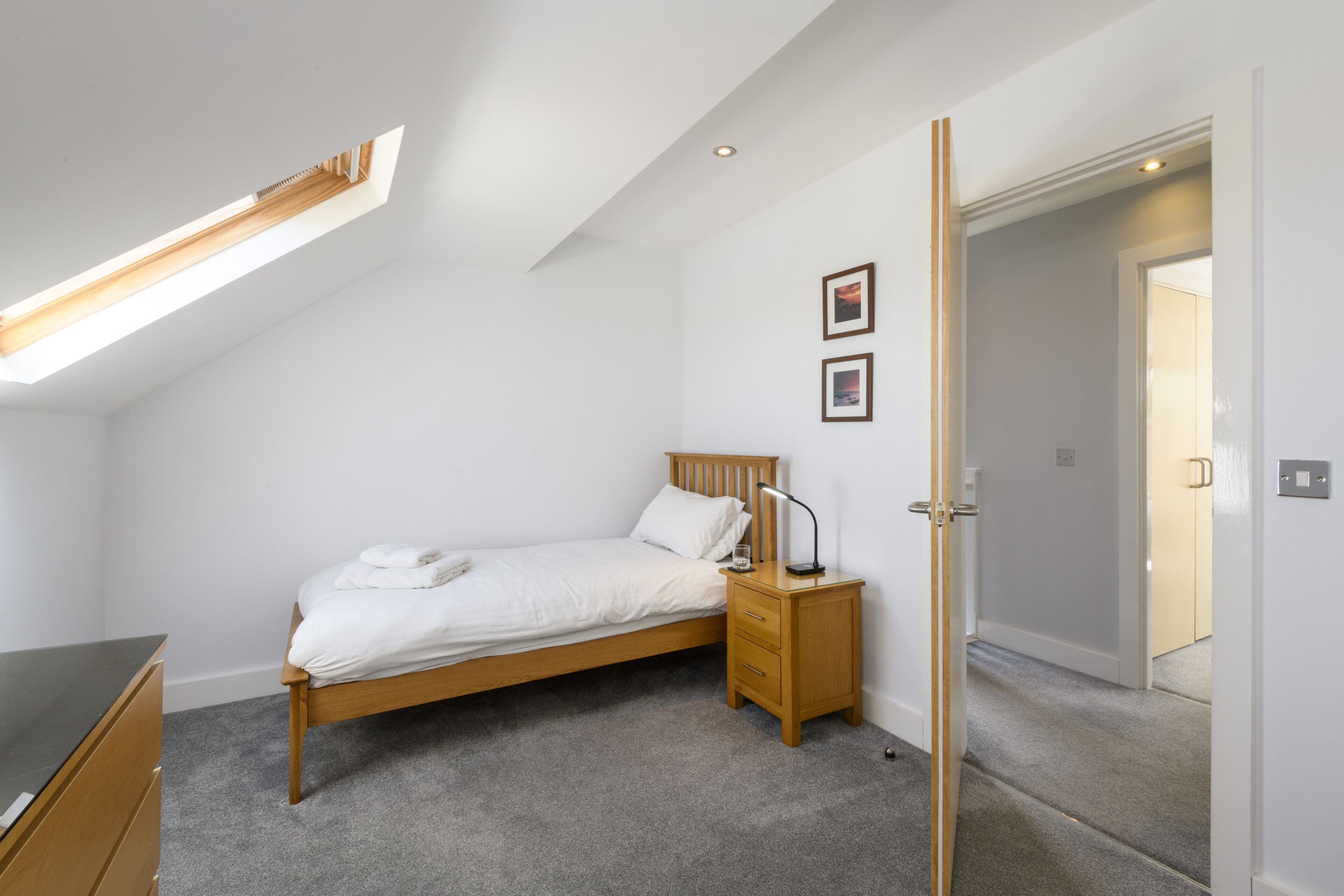 A bedroom with a single bed, a nightstand, a desk, and a ceiling light.