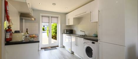 A modern kitchen with a washing machine, a toaster, and a sink.