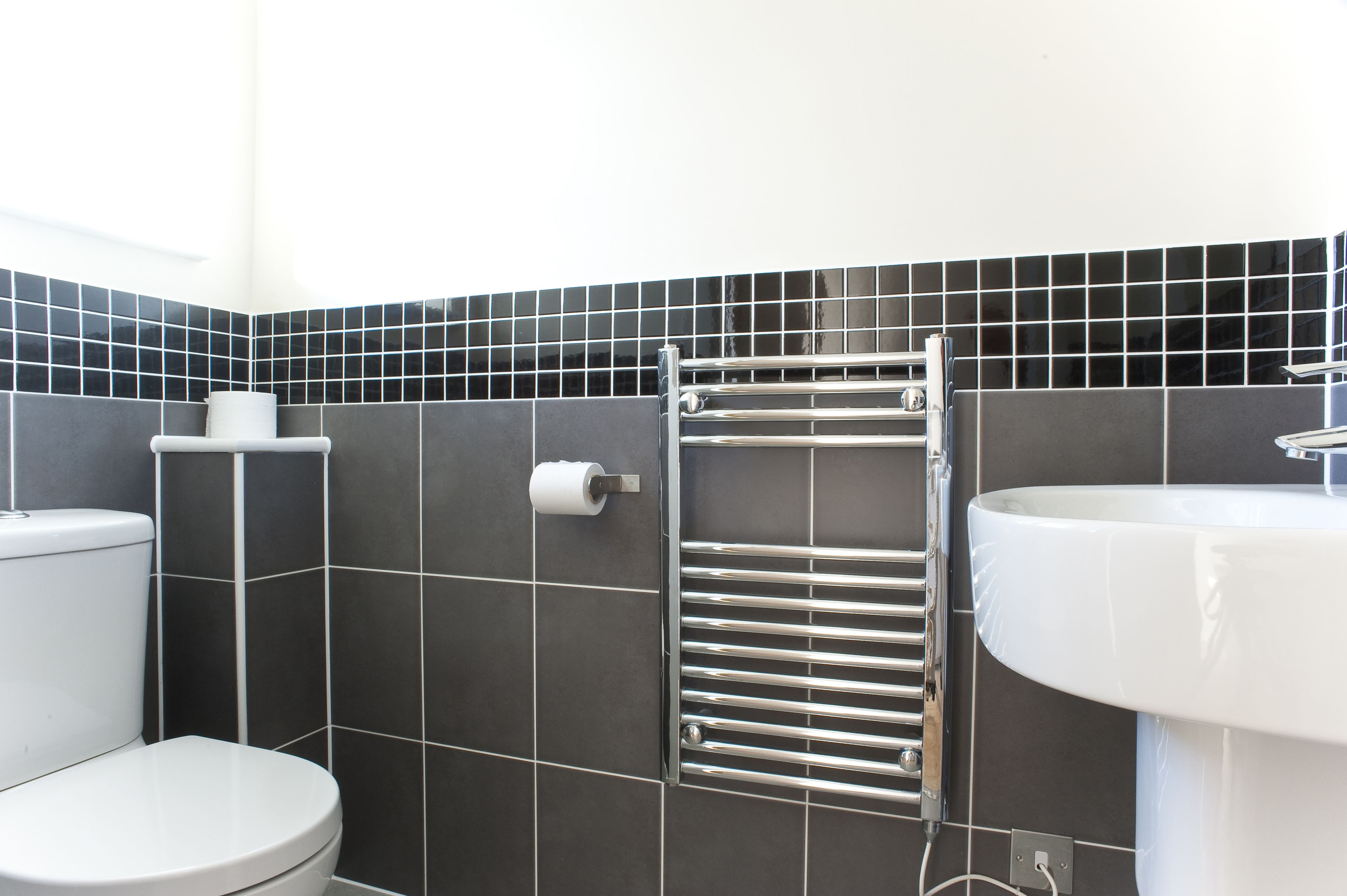 A modern bathroom with a toilet, a towel rack, and a sink.