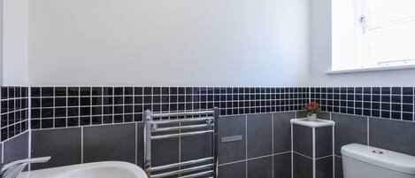 A bathroom with a white sink, a towel rack, a toilet, and a window with a view.