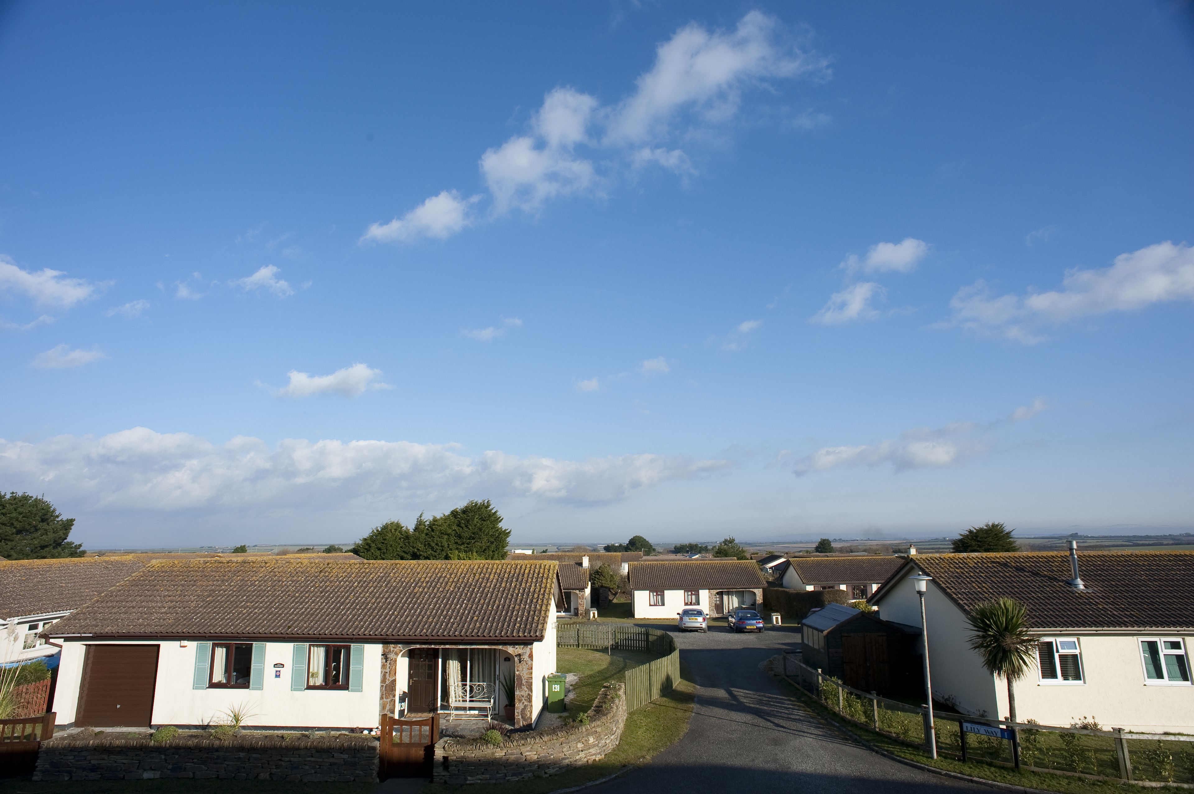 A residential street with houses, a clear sky, and a distant view of the horizon.