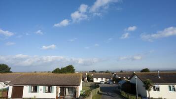 Une rue résidentielle bordée de maisons, un ciel dégagé et une vue lointaine sur l’horizon.