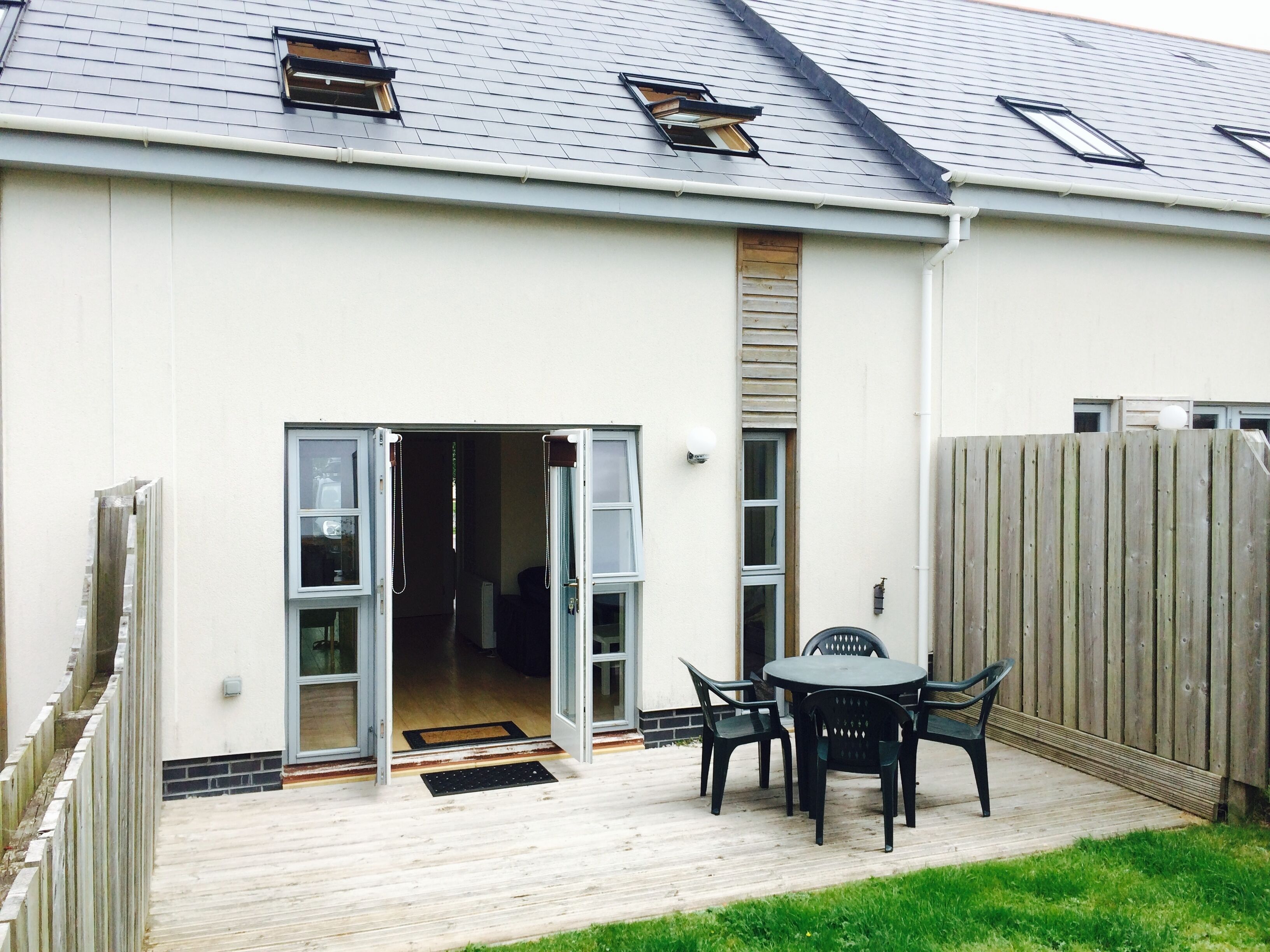 A house with a deck, a sliding glass door entrance, and a fenced backyard.