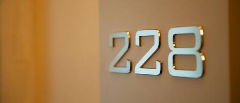 A close-up of a metallic number sign with the digits '228' mounted on a wall.