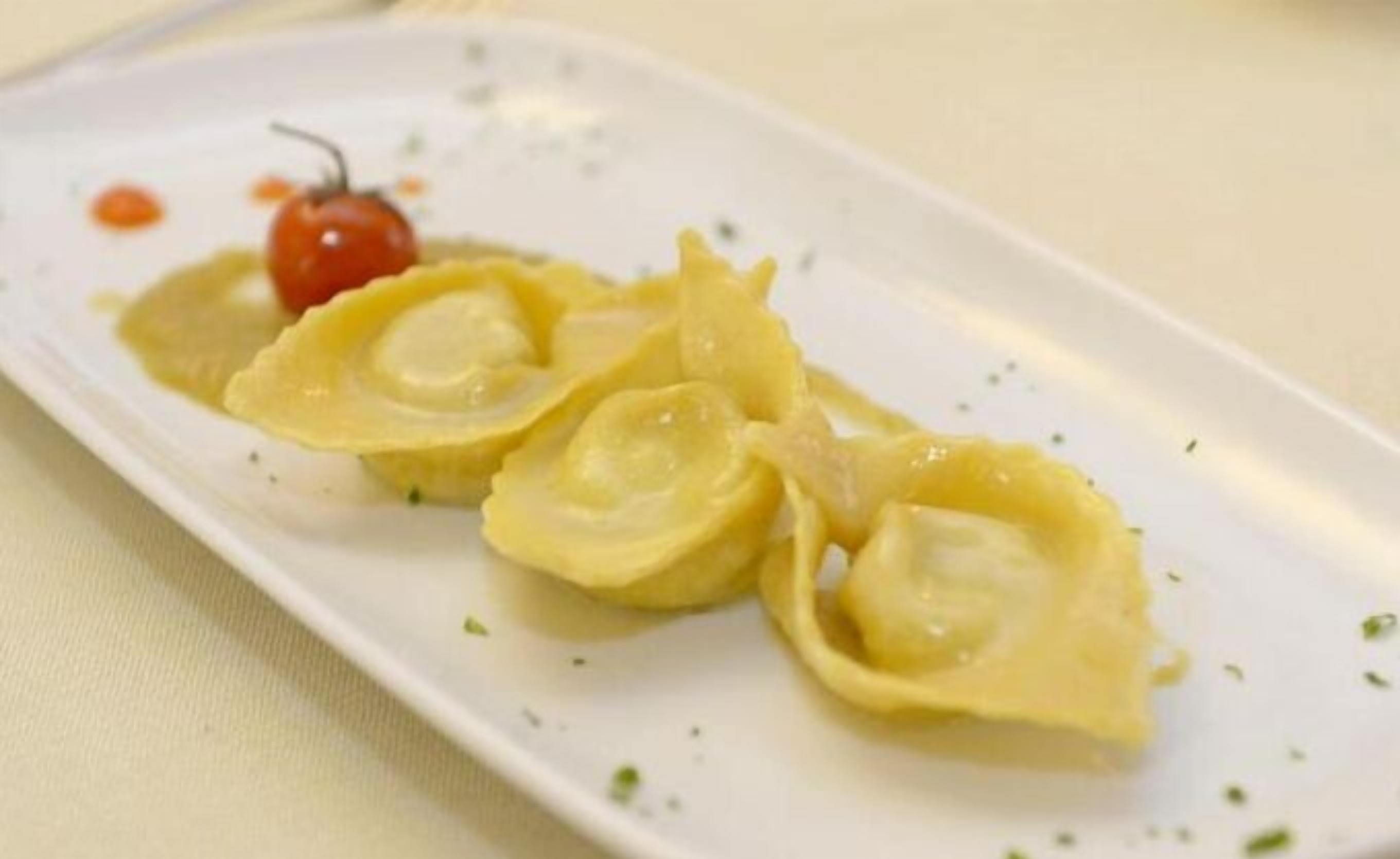 Ein Teller mit Ravioli und einer Kirschtomate.