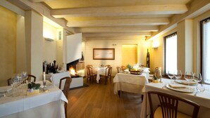 Un espace repas agrémenté de poutres en bois, de nappes blanches et d’une cheminée.