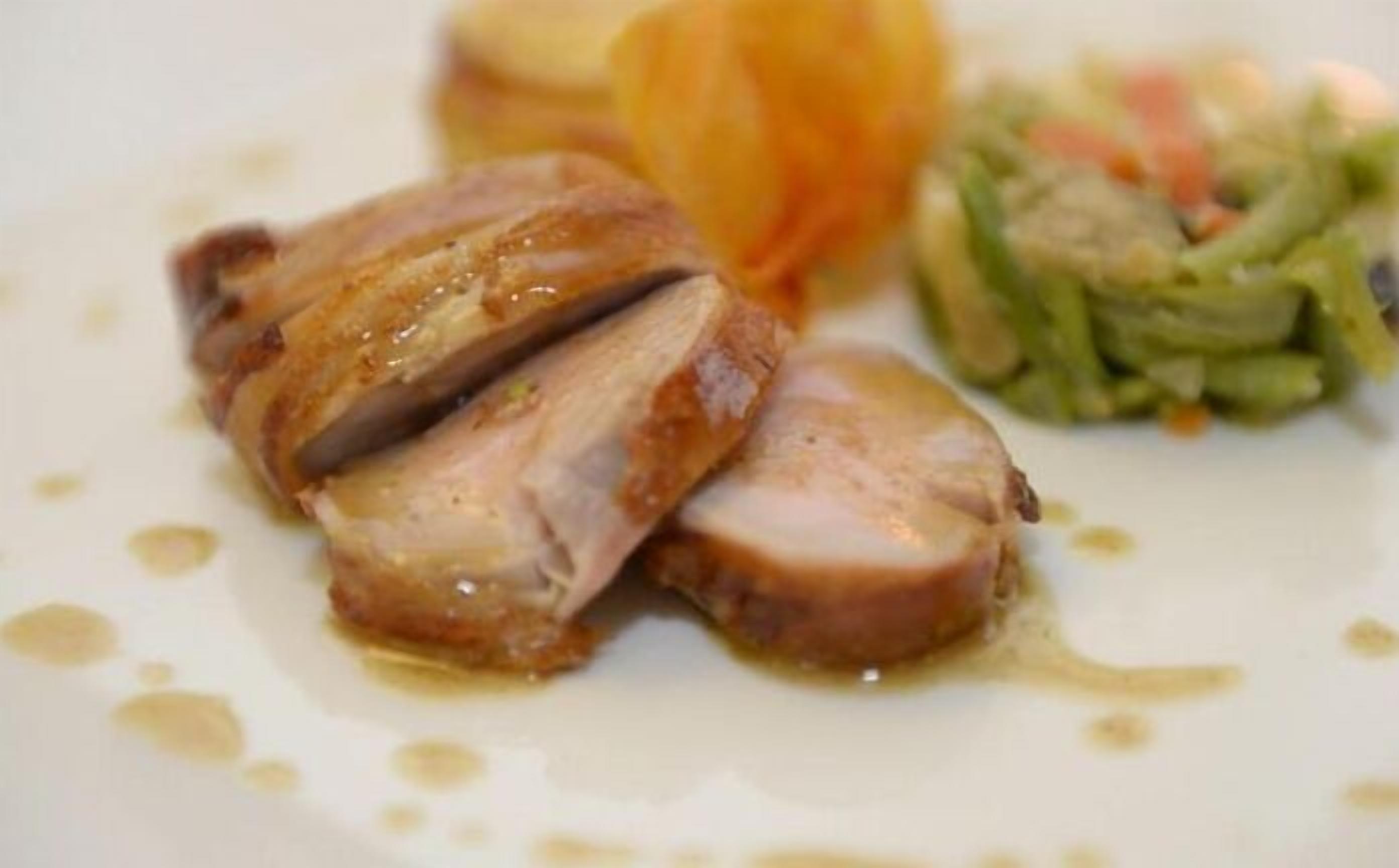 A plate with sliced meat, a piece of carrot, and a green vegetable dish.