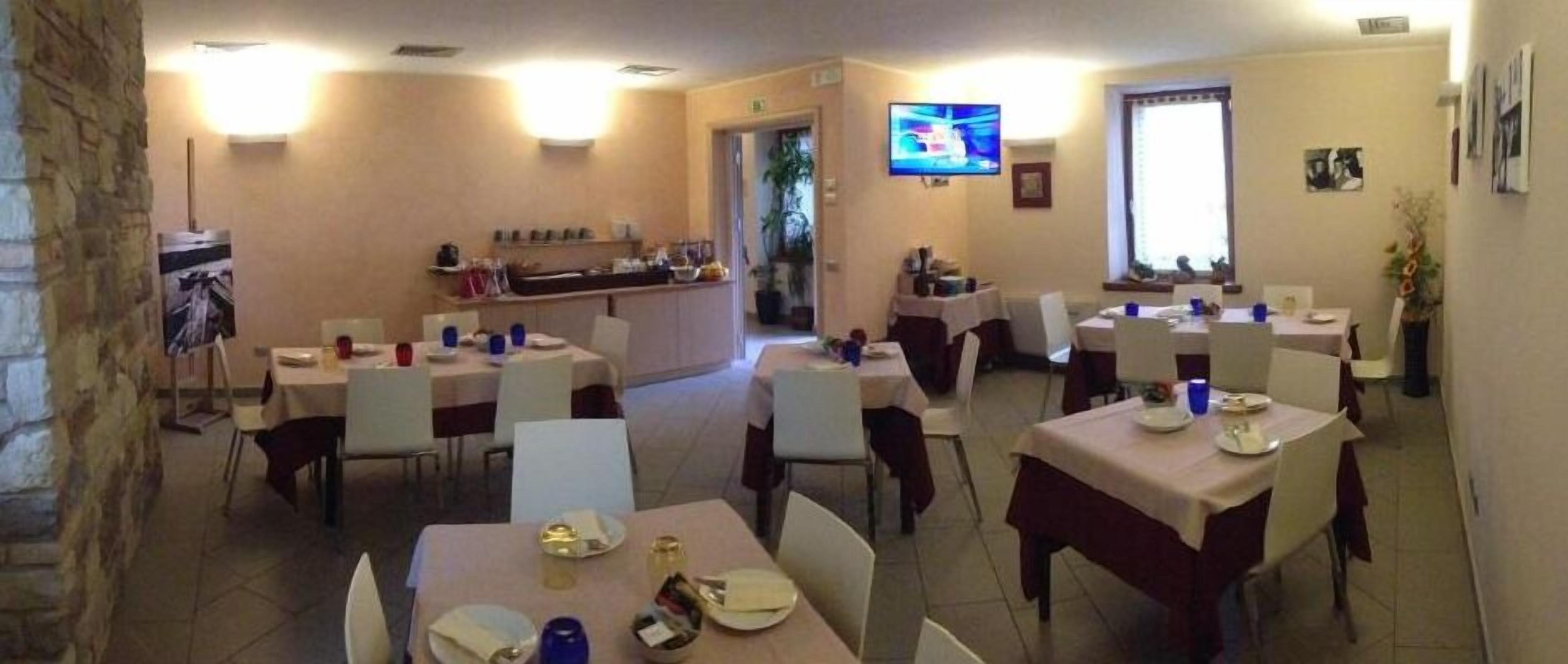 A dining area with multiple tables and chairs, a television mounted on the wall, and a counter with various items.