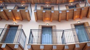 Un immeuble à plusieurs étages, doté de balcons, de poutres en bois et d’un logo sur le toit.